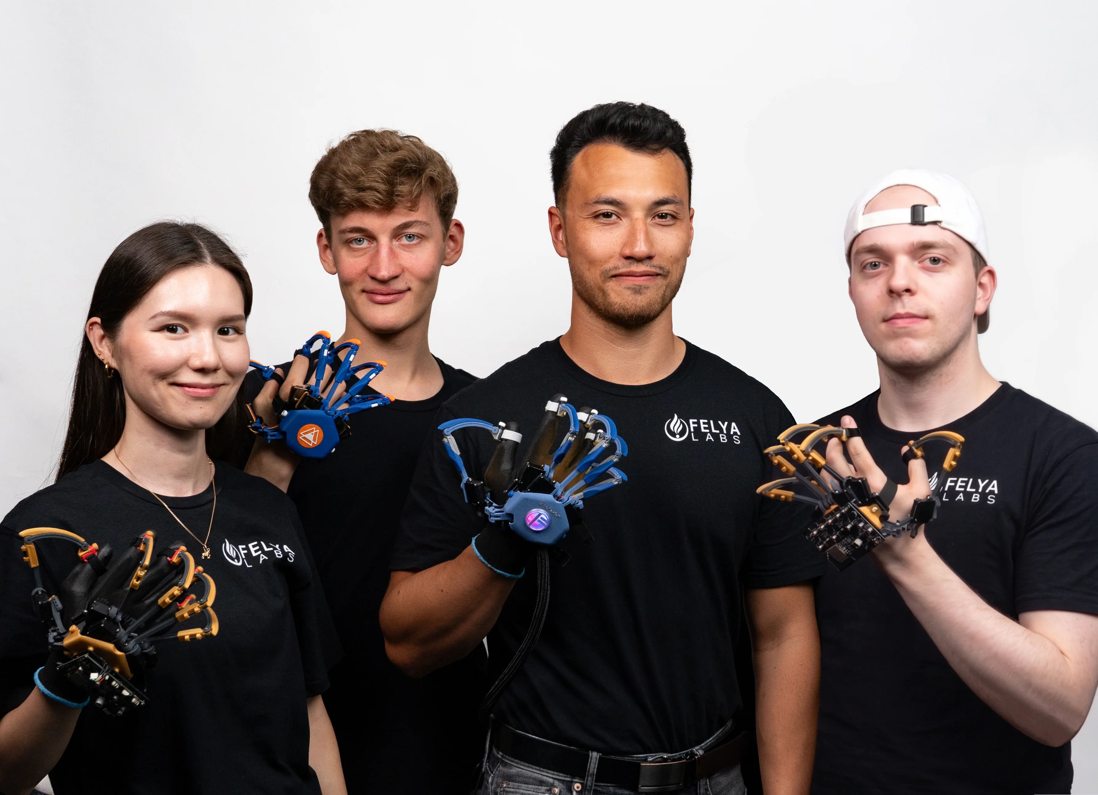 Four FELYA LABS team members holding and wearing haptic glove prototypes.